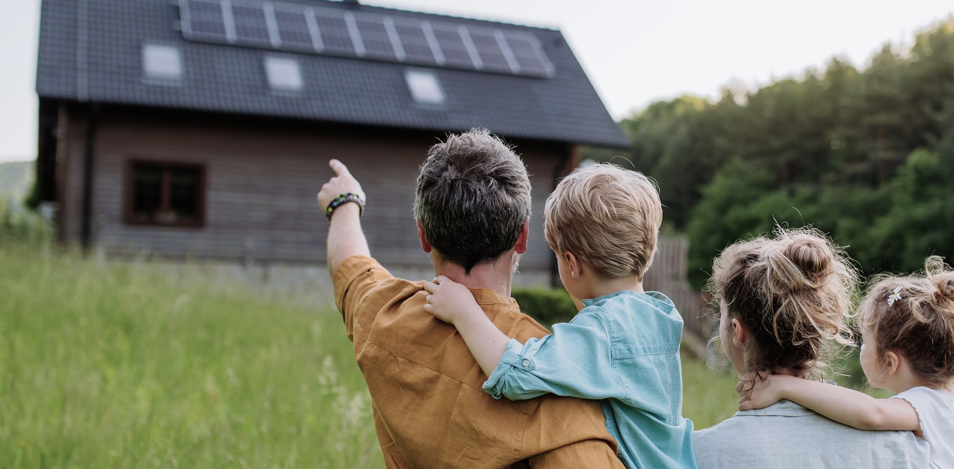 Familie auf einer Wiese vor einem Haus